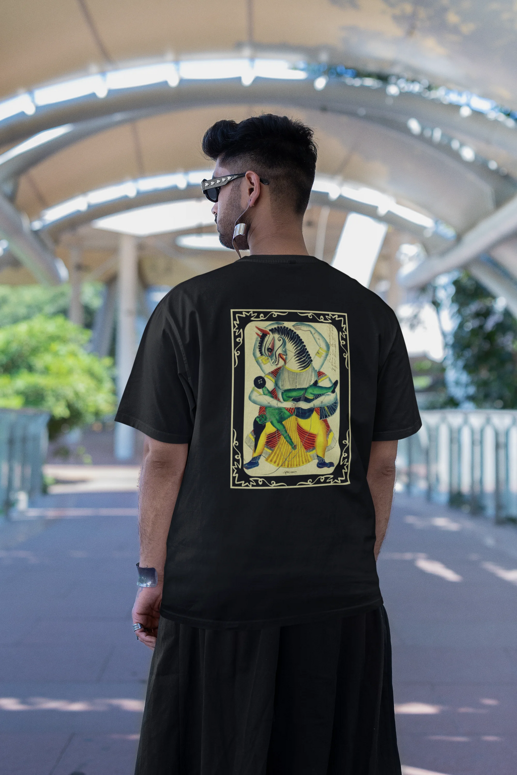 Person wearing a black t-shirt with a colorful graphic design outdoors.